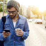 Modern young man with mobile phone in the street.